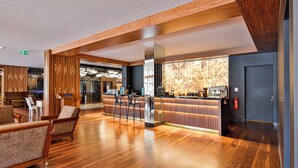 Un hall espacioso con suelo de madera, zona de estar y un bar de diseño moderno.