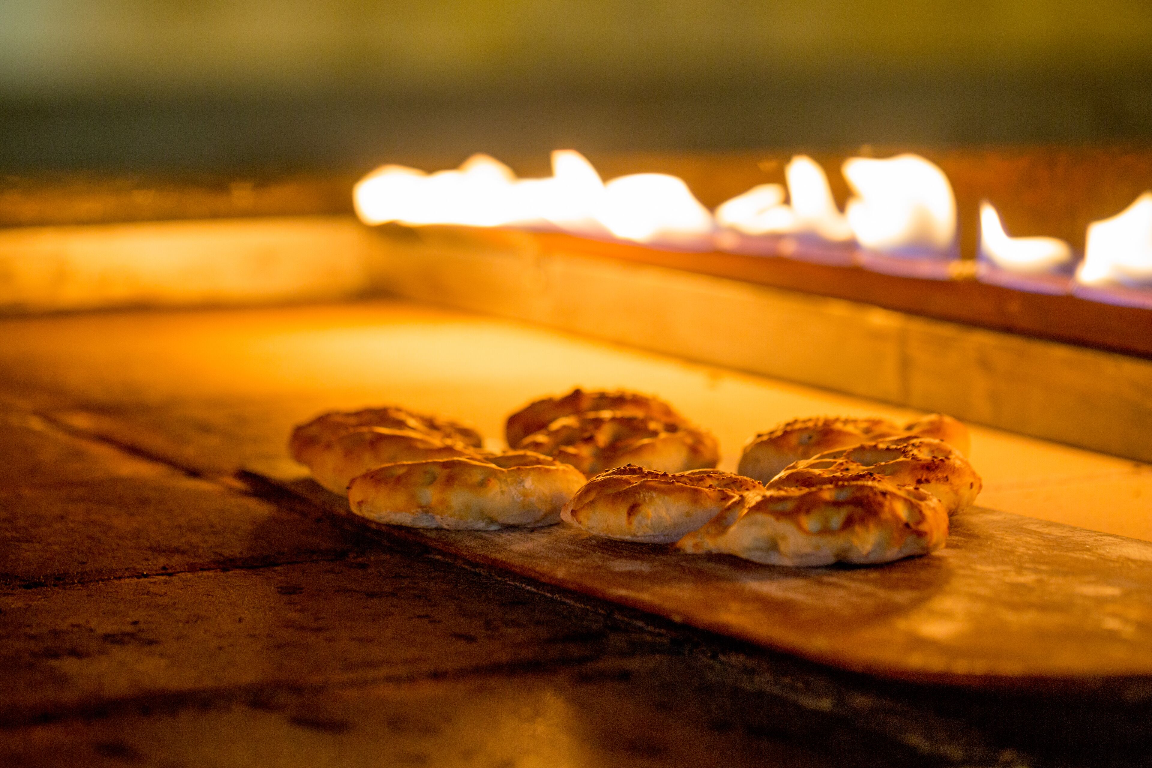 A wooden surface with several baked goods, possibly pastries, and a glowing fire in the background.