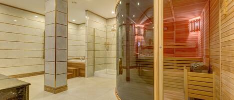 Un área de spa moderna con sauna de vidrio, suelo de mármol y bancos de madera.
