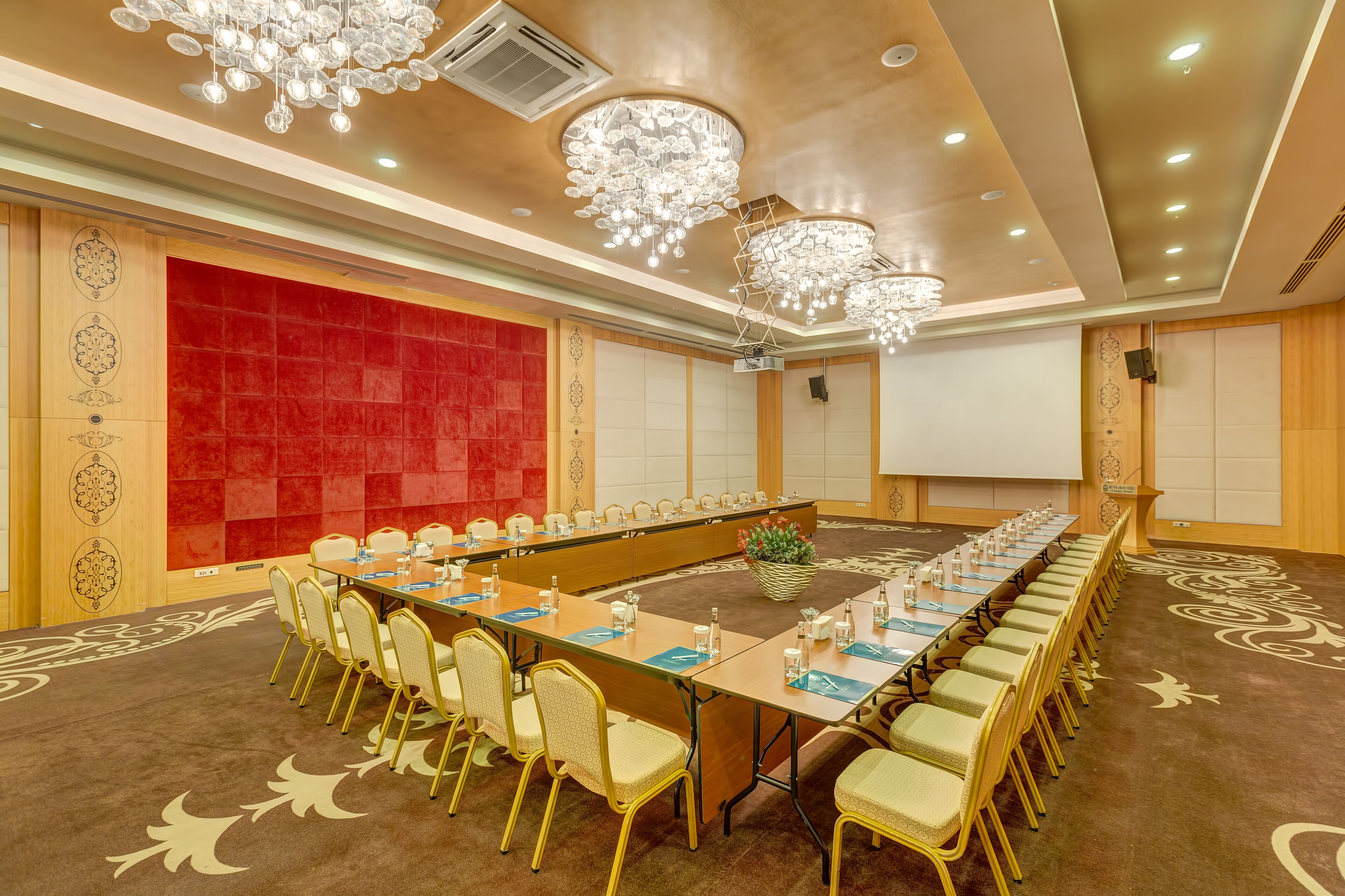 A conference room with a long table, chairs, and a projector screen.