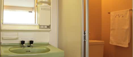 A bathroom with a green sink, a toilet, and a glass shower enclosure.