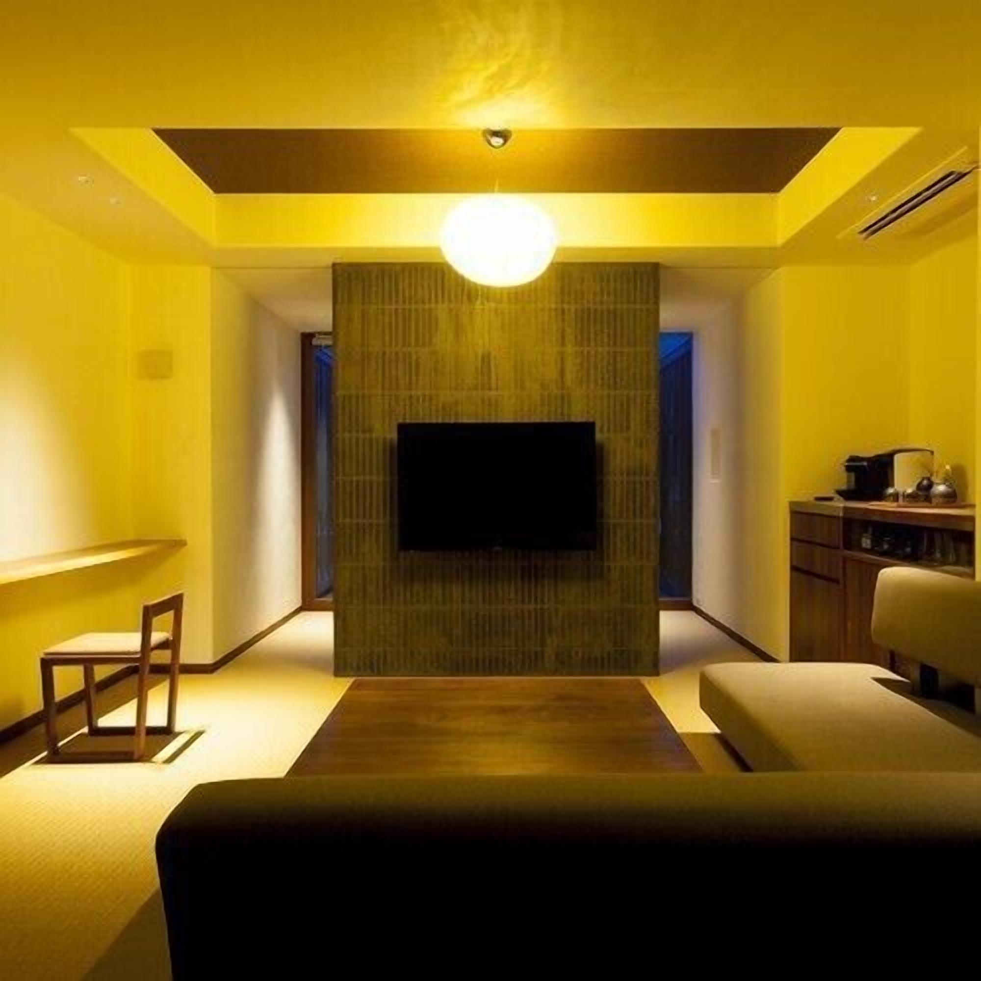 Un salon moderne avec un téléviseur à écran plat fixé à un mur texturé, un canapé, une table basse et une lampe.
