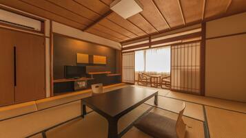 A traditional Japanese room with tatami flooring, a low table, a television, and sliding doors.