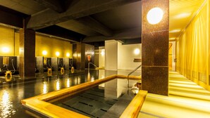 Área interna de piscina moderna, com destaque para um recurso aquático central, várias estações de chuveiro e um corredor iluminado em amarelo.