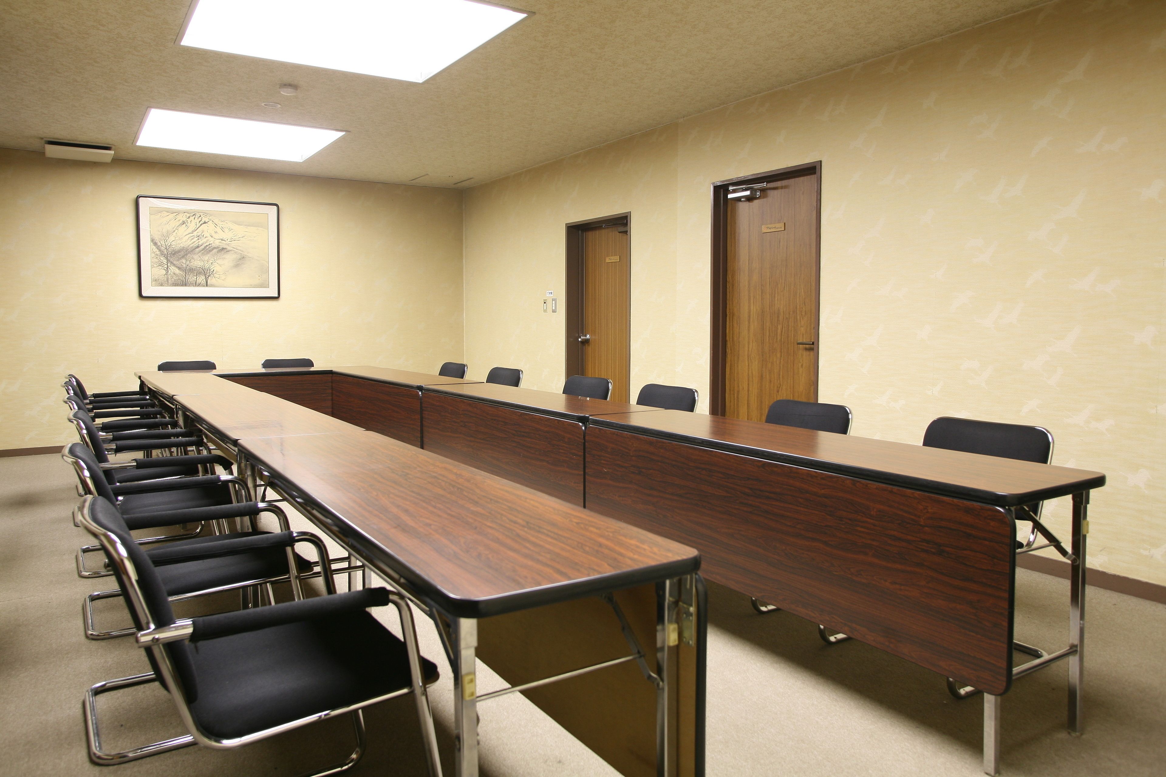 A conference room with a long table, chairs, and a framed picture on the wall.