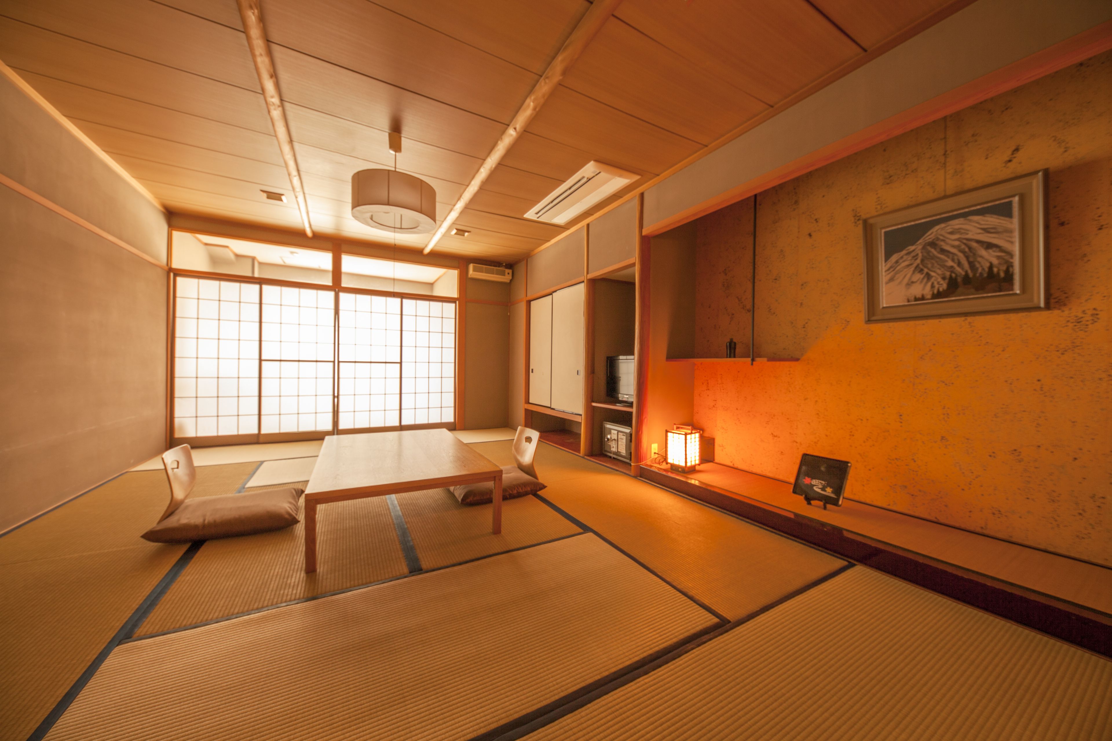 Une pièce traditionnelle japonaise avec un sol recouvert de tatamis, une table basse, un banc rembourré et une porte coulissante de type shoji.