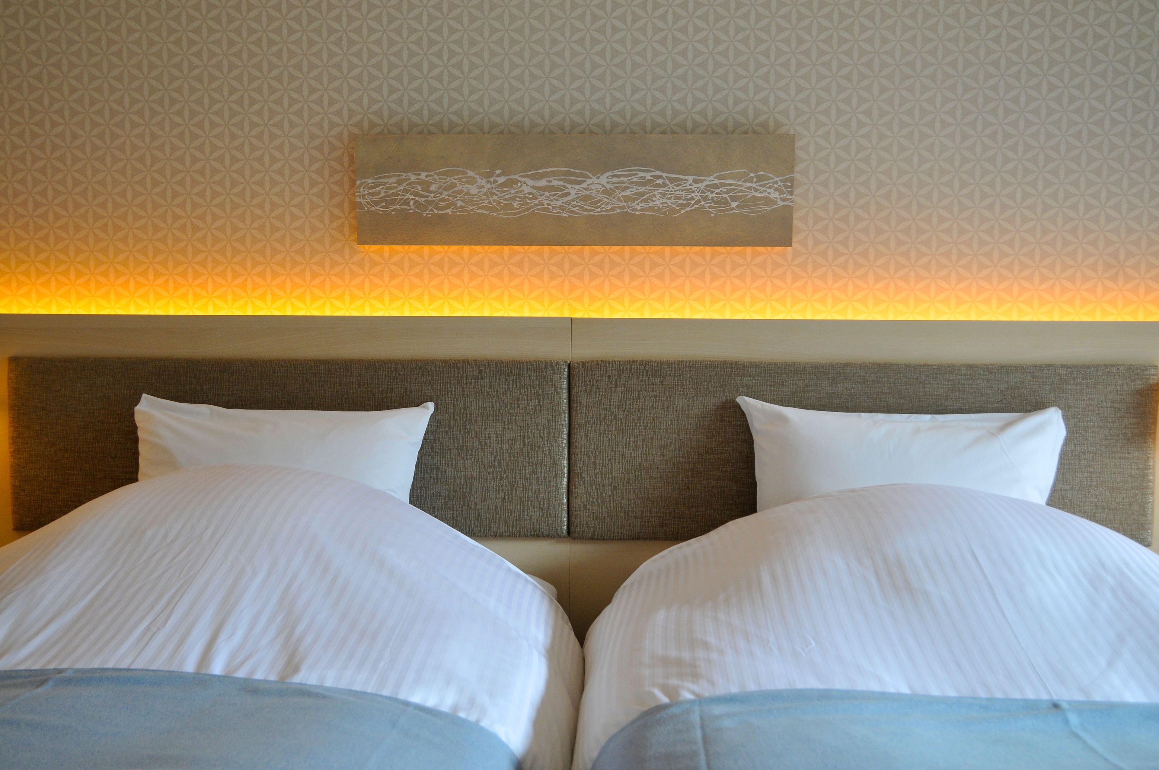 A hotel room with a large bed, two pillows, and a headboard.