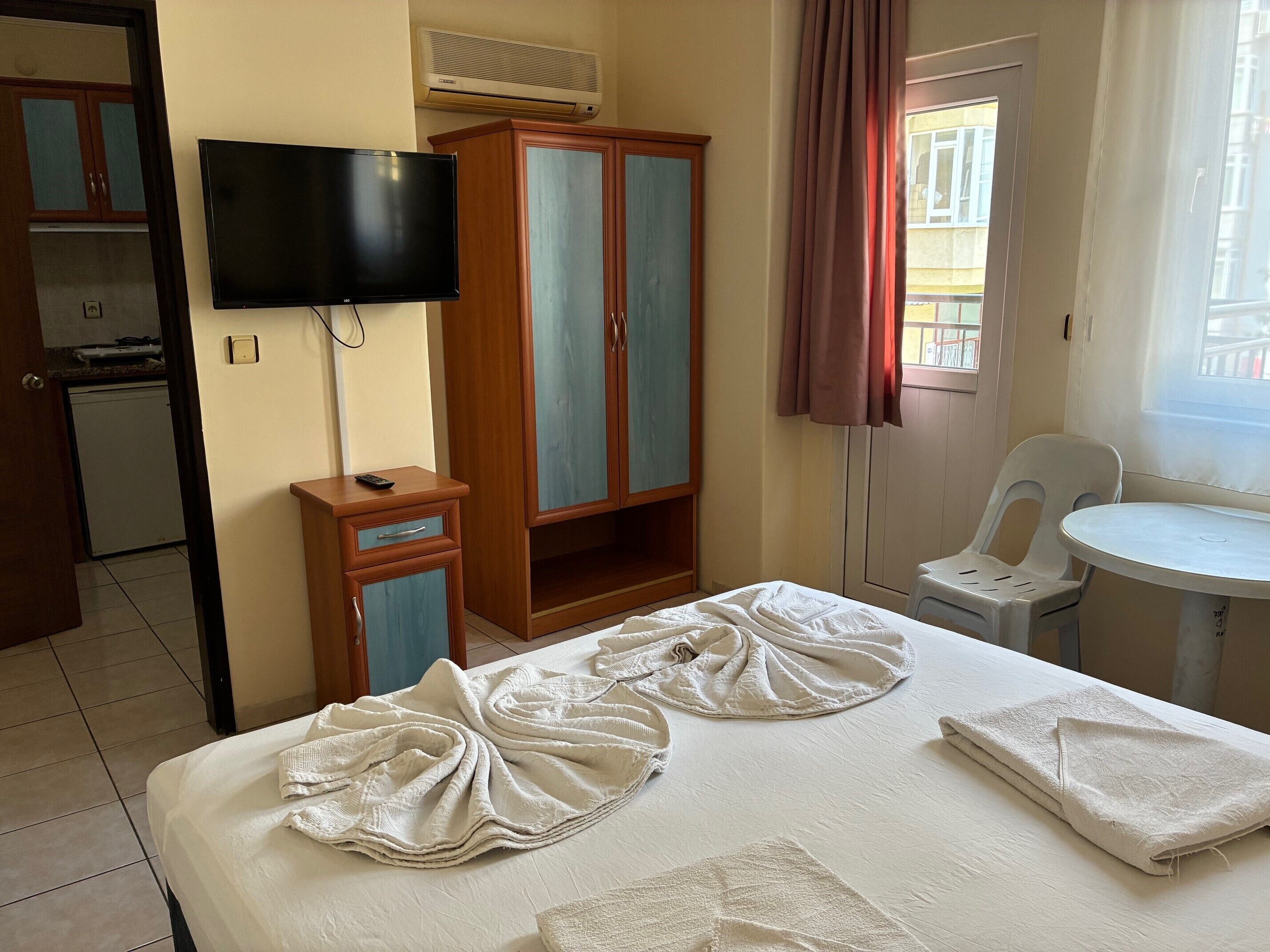 A hotel room with a bed, a television, a wardrobe, a small table, and a chair.