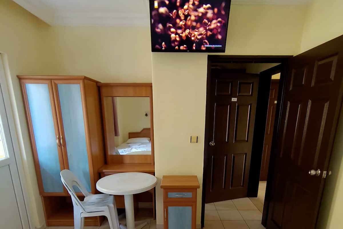 A hotel room with two beds, a small table, a chair, a television, and a wardrobe.