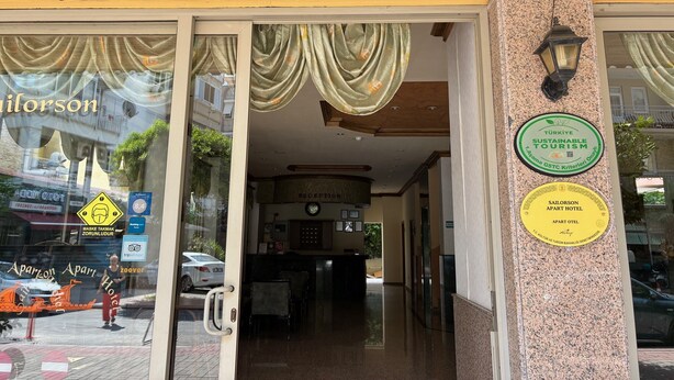 La entrada del Sailorson Apart Hotel, con un área de recepción visible en el interior.