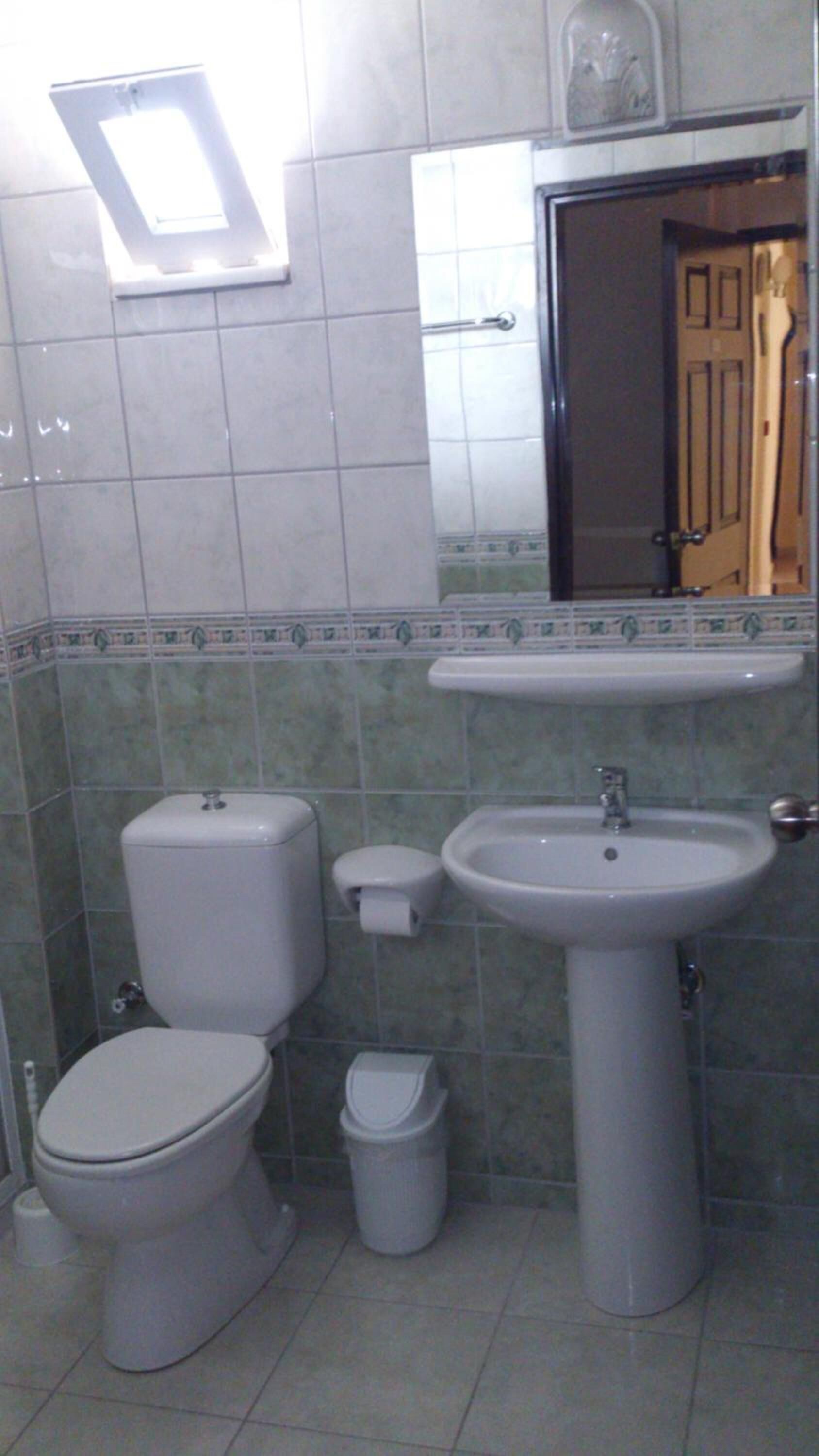 Un baño con inodoro, bidé, lavamanos y un espejo sobre el lavabo.