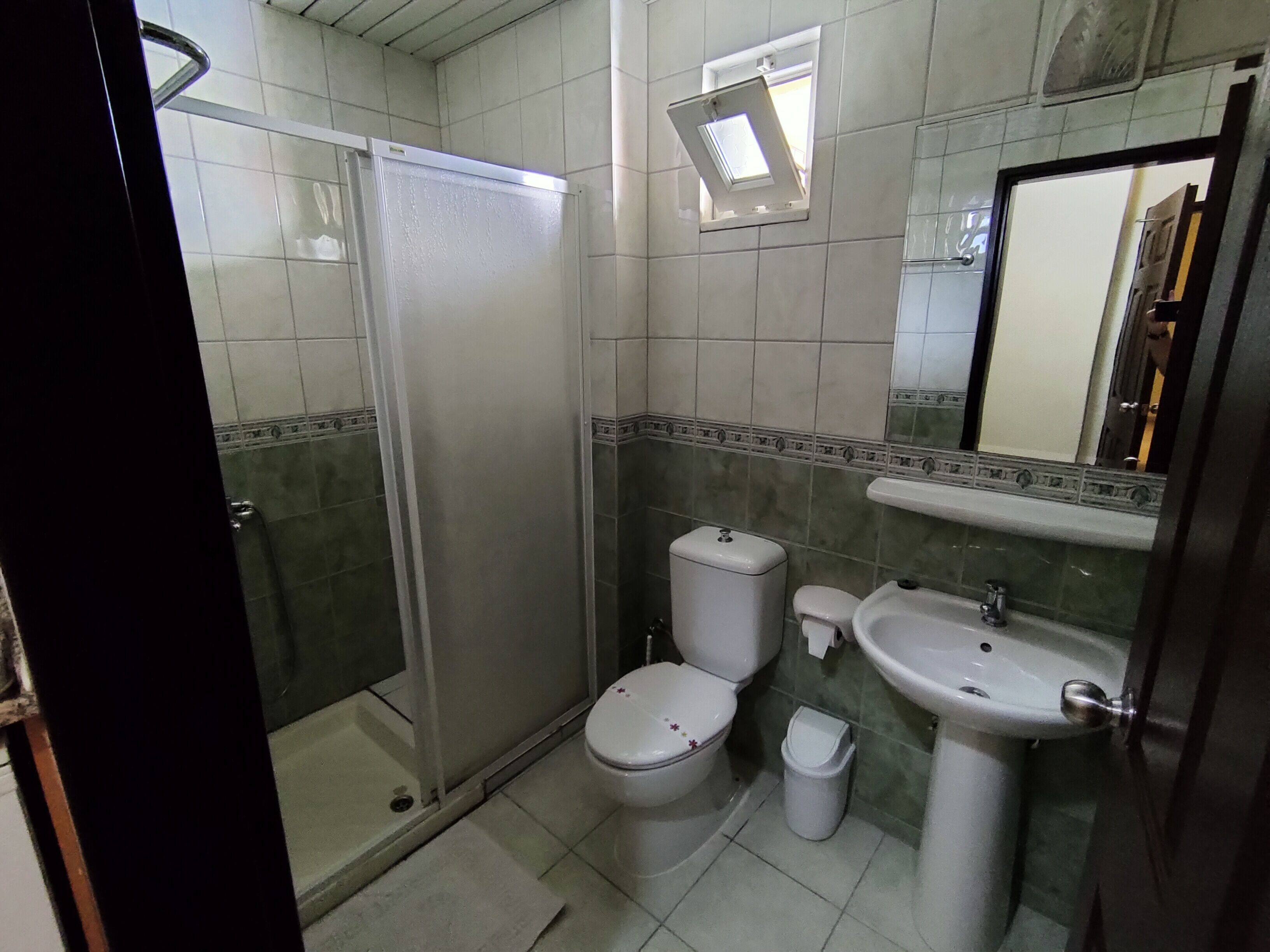 A bathroom with a toilet, sink, and shower.