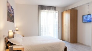 Ein Schlafzimmer mit einem Bett, Nachttischlampen, einem Fernseher und einem Kleiderschrank.