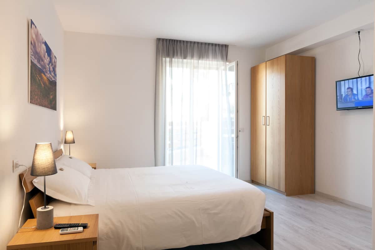 Une chambre à coucher avec un lit, des lampes de chevet, une télévision et une armoire.
