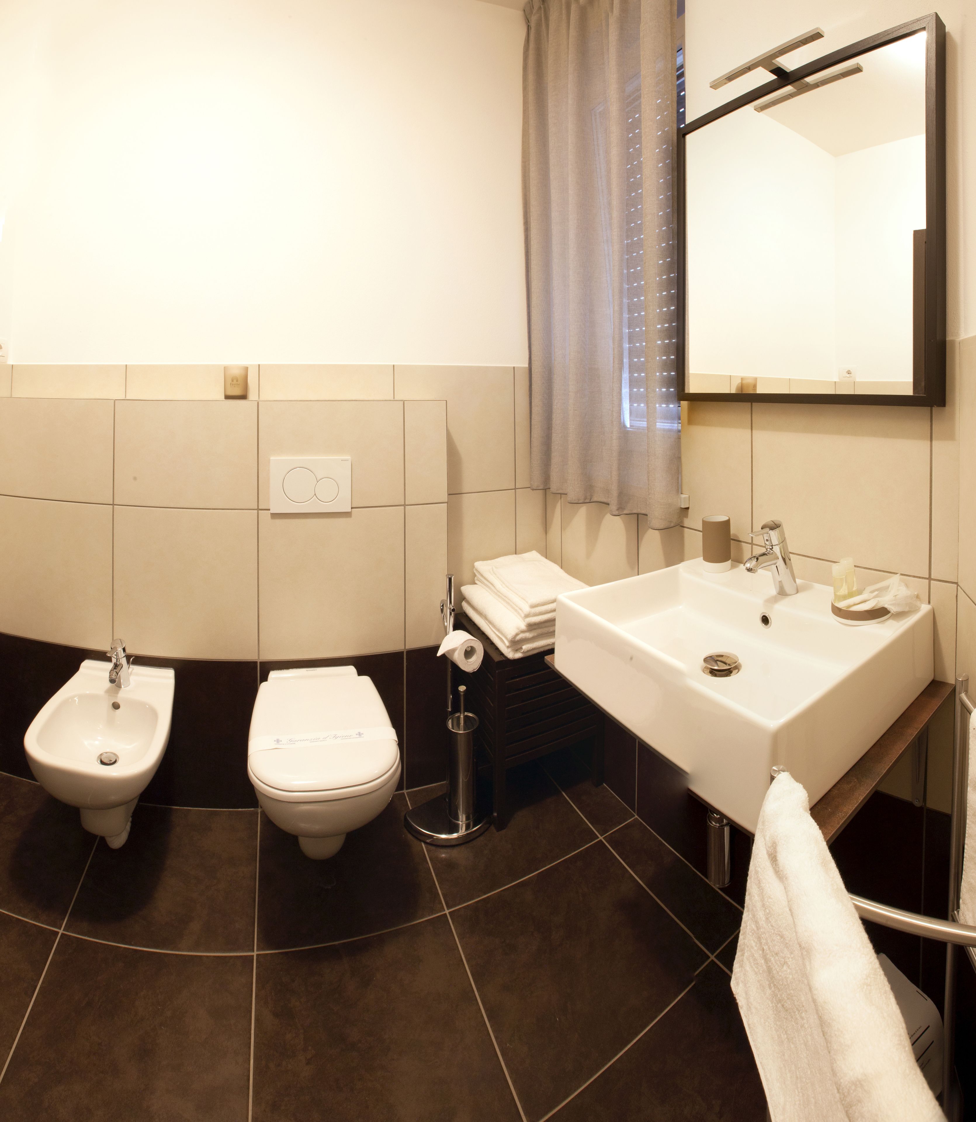 Ein Badezimmer mit Bidet, Toilette, Waschbecken und Spiegel.