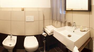 Ein Badezimmer mit Bidet, Toilette, Waschbecken und Spiegel.