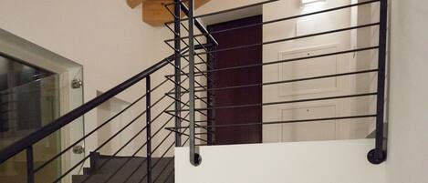 Una escalera de varios niveles con barandillas negras y vigas de madera.
