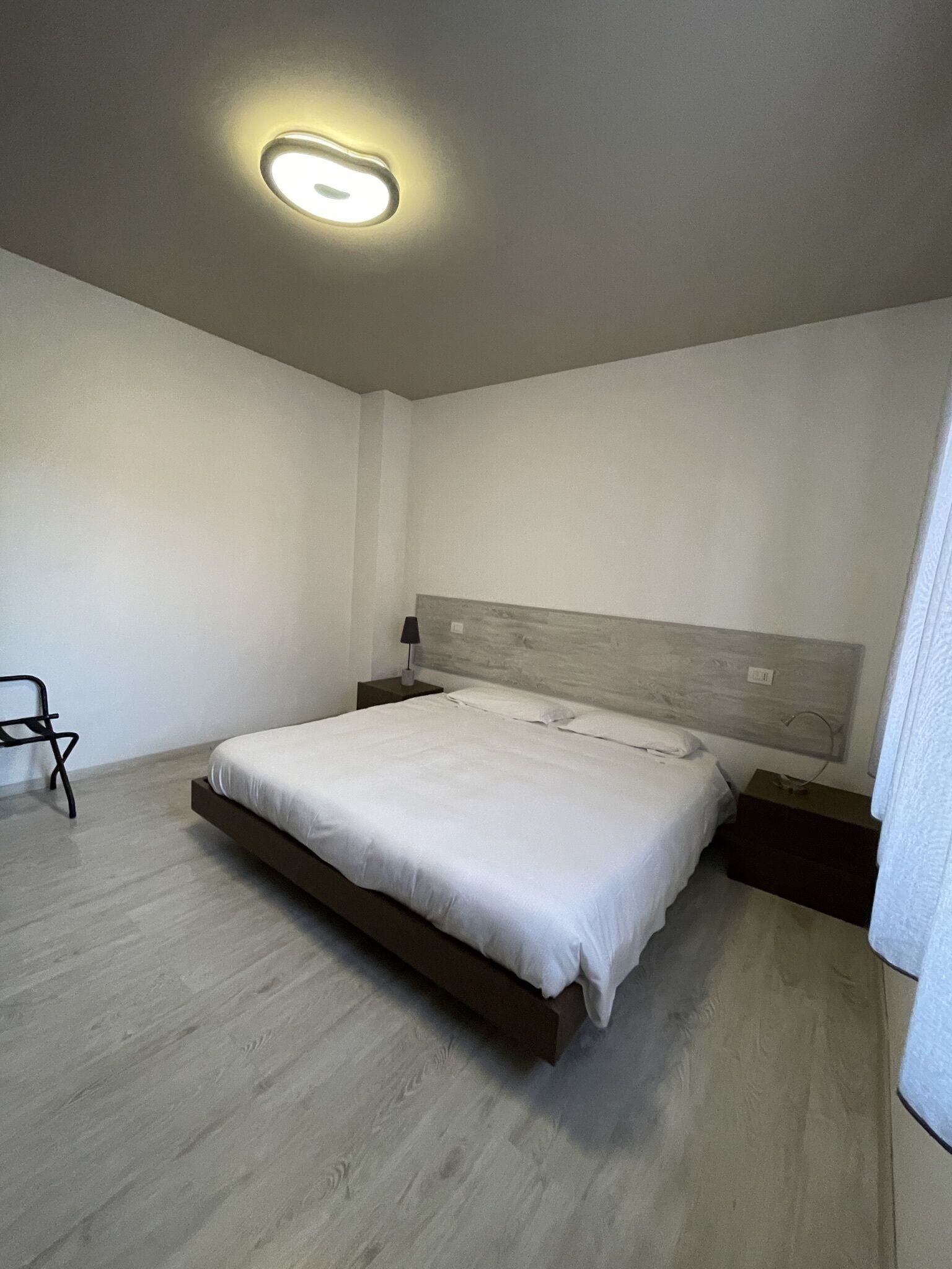 Ein modernes Schlafzimmer mit Bett, Nachttischen und einem Sessel.
