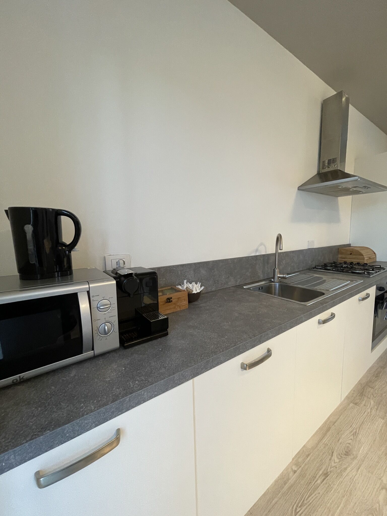 A modern kitchen with a microwave, coffee maker, sink, and stove.