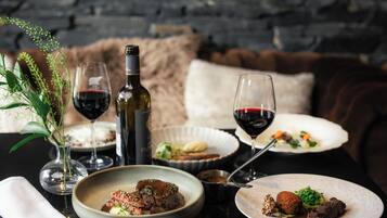 A dining table with plates of food, wine glasses, and a bottle of wine.