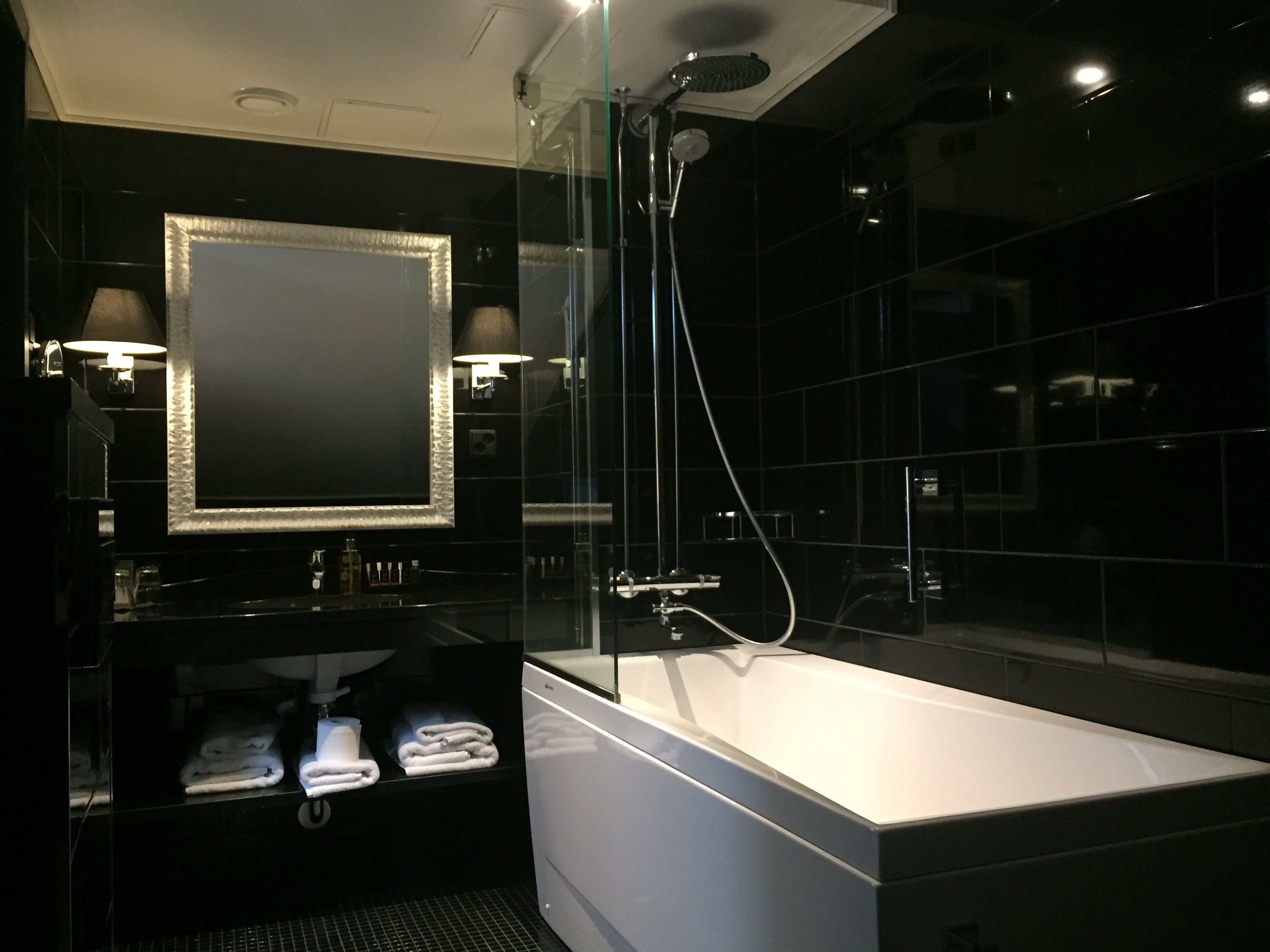 A modern bathroom with a large mirror, a bathtub, and a glass-enclosed shower area.