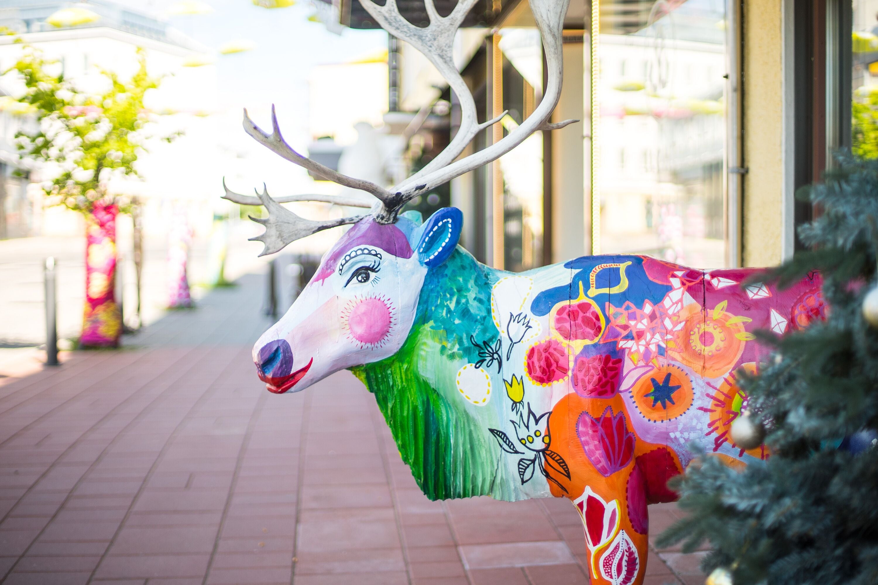 A colorful deer sculpture on a brick pathway.