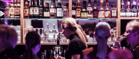 Een bar met drankflessen en glazen op de planken.