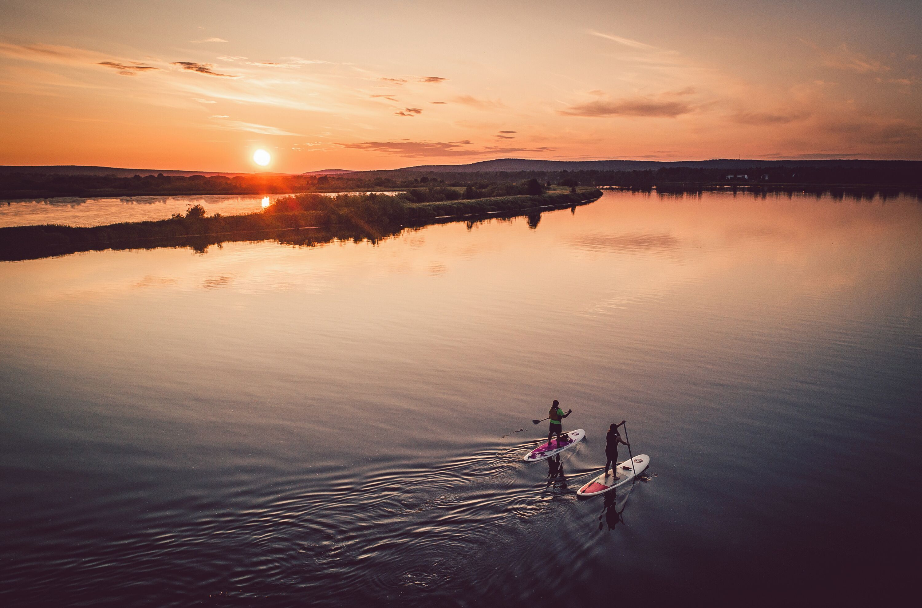 A calm lake at sunset with paddleboards.