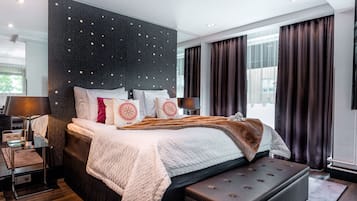 Une chambre moderne avec un grand lit, une table de chevet avec une lampe, un téléviseur à écran plat et une grande fenêtre avec des rideaux.