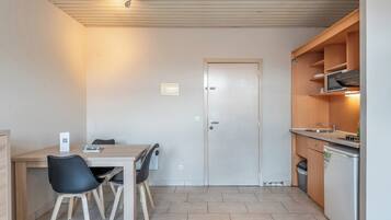 Una cocina compacta con comedor, una puerta y un pequeño cubo de basura.