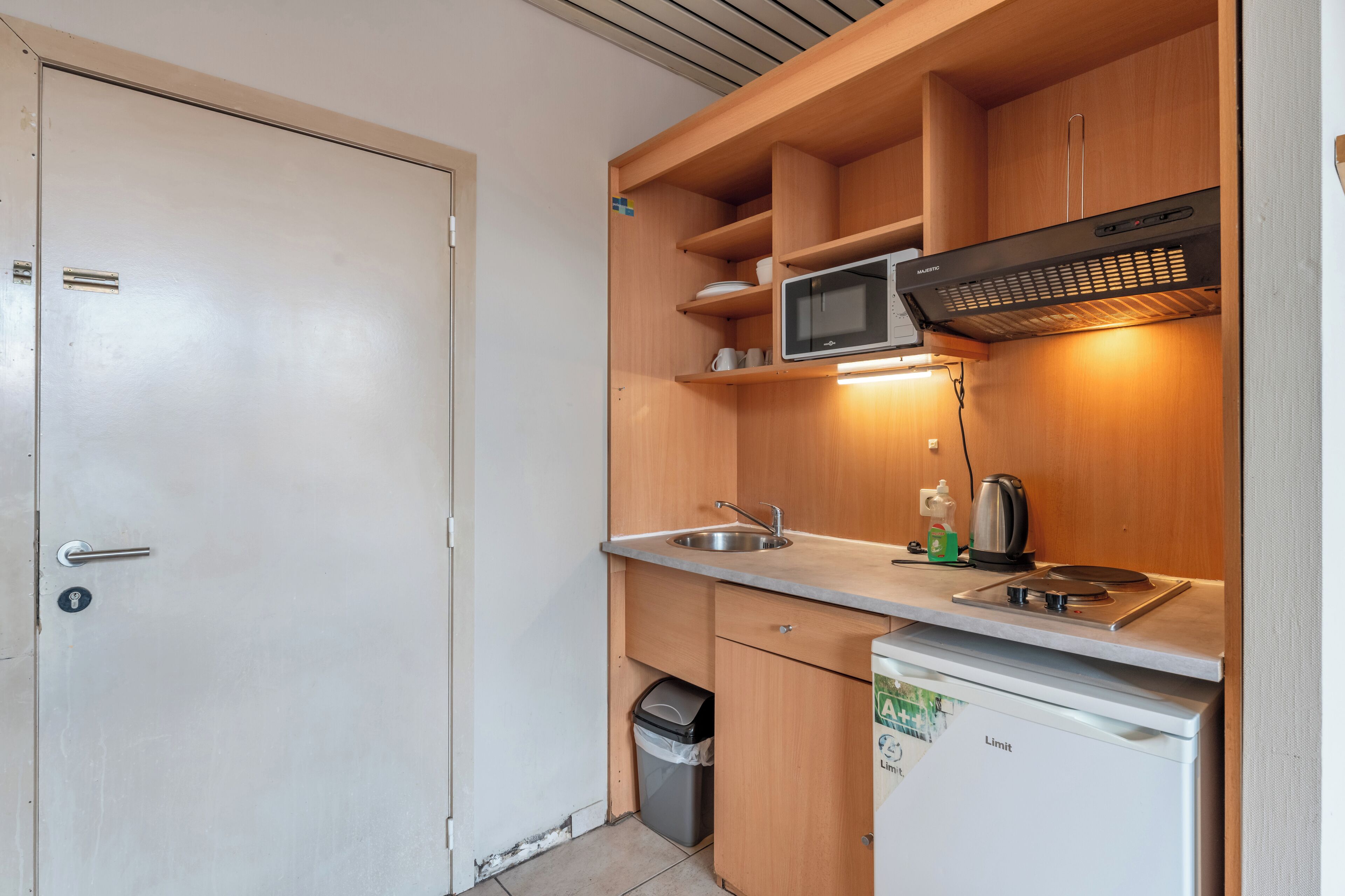 A compact kitchenette with a microwave, sink, and a small refrigerator.