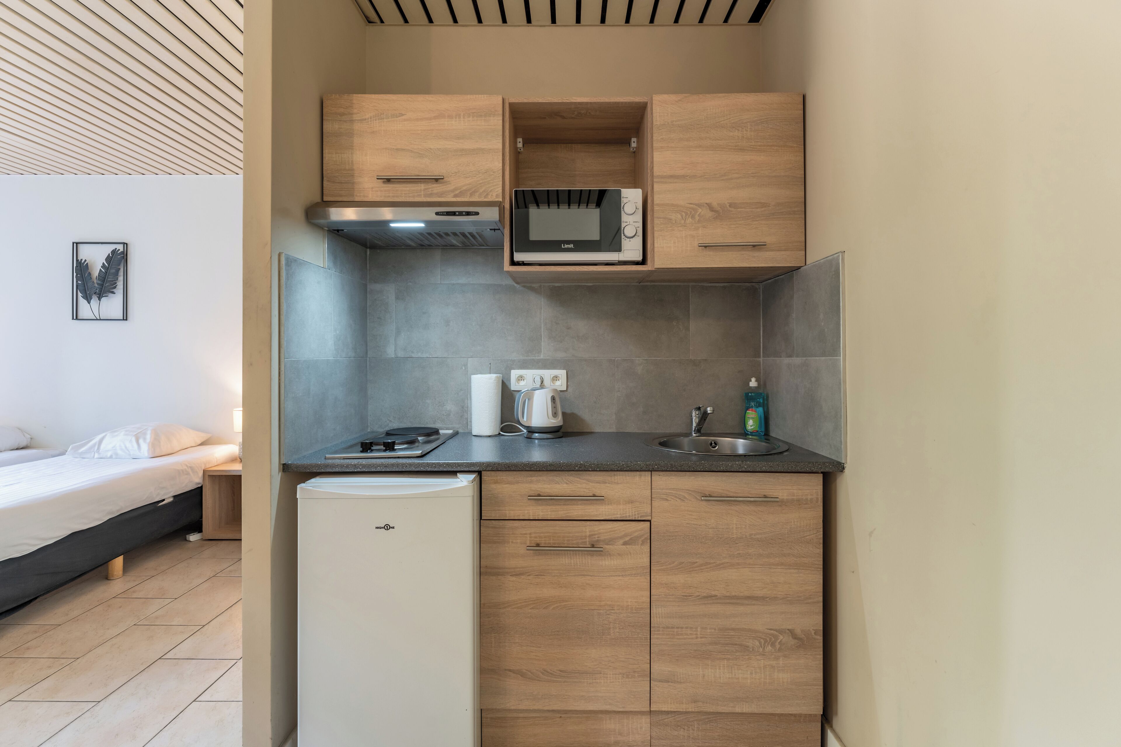 A compact kitchenette with a microwave, kettle, and sink.
