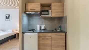 A compact kitchenette with a microwave, kettle, and sink.
