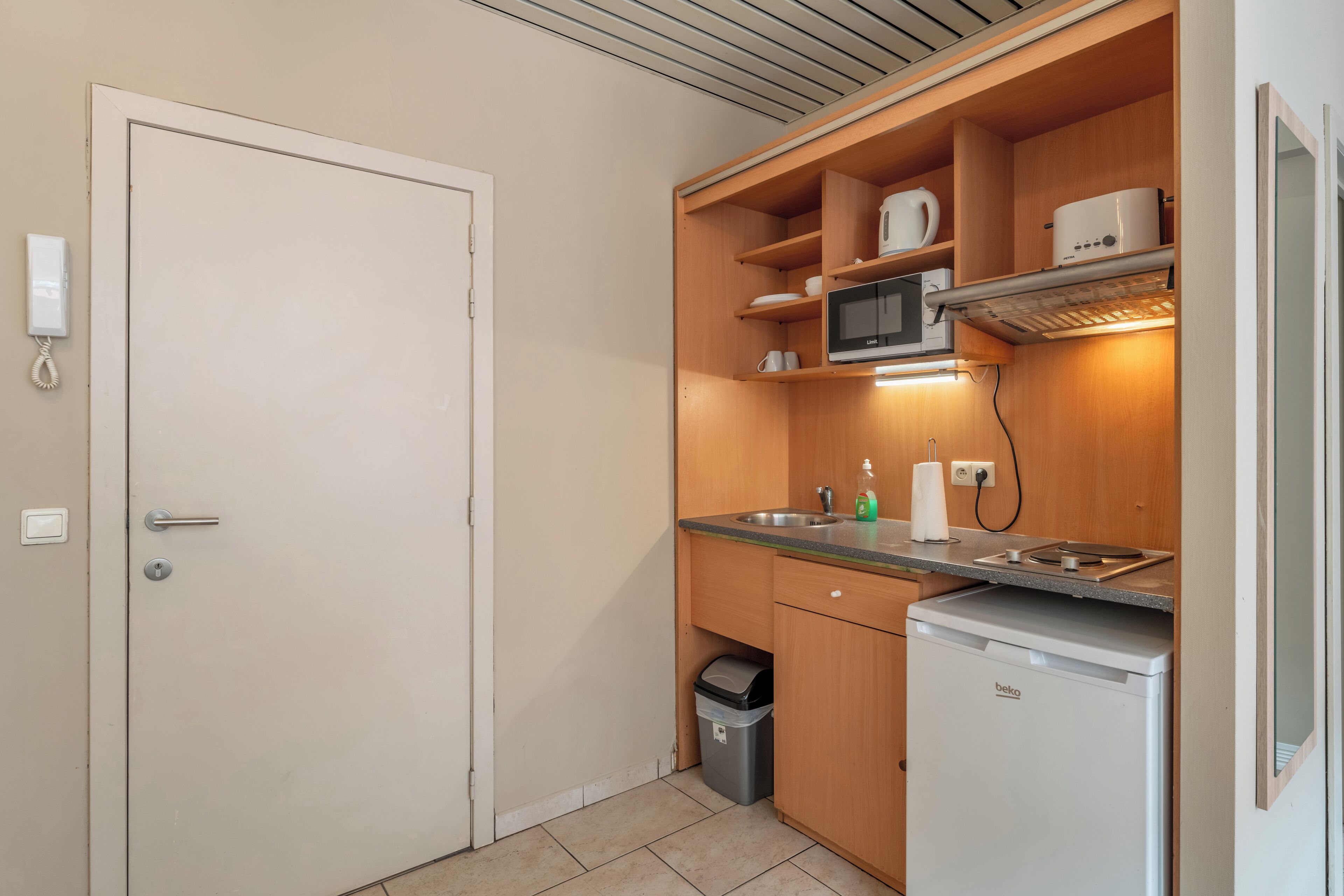 A compact kitchen with a microwave, sink, and a small refrigerator.