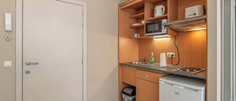 A compact kitchen with a microwave, sink, and a small refrigerator.
