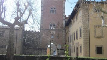 Un cortile con una torre storica, una fontana e un edificio con un balcone.