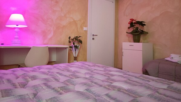 A bedroom with a bed, a desk, a chair, a wardrobe, and a bedside table with a lamp. - Hotel Il Ponte (Cecina)