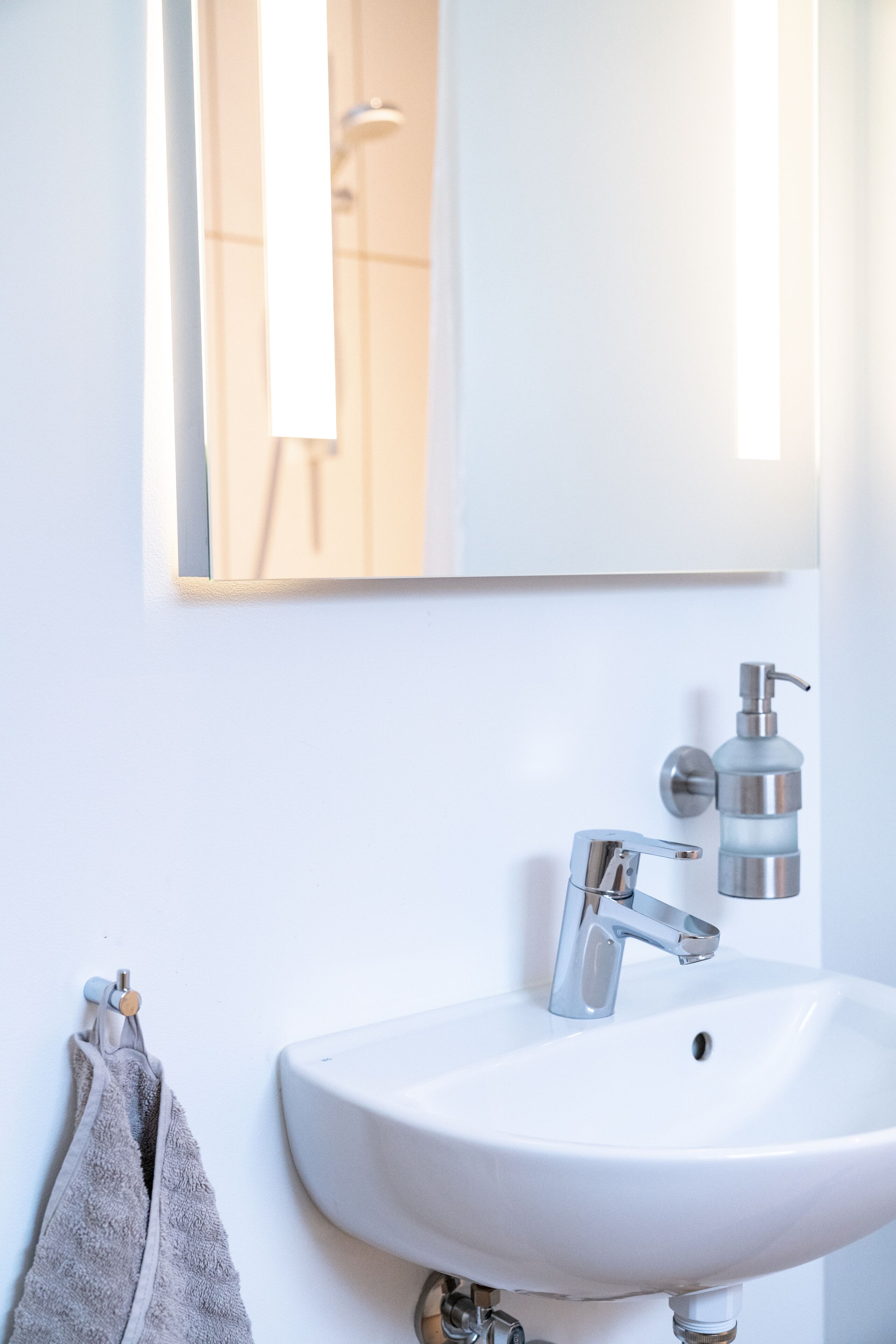 A bathroom with a white sink, a mirror, and a towel rack.