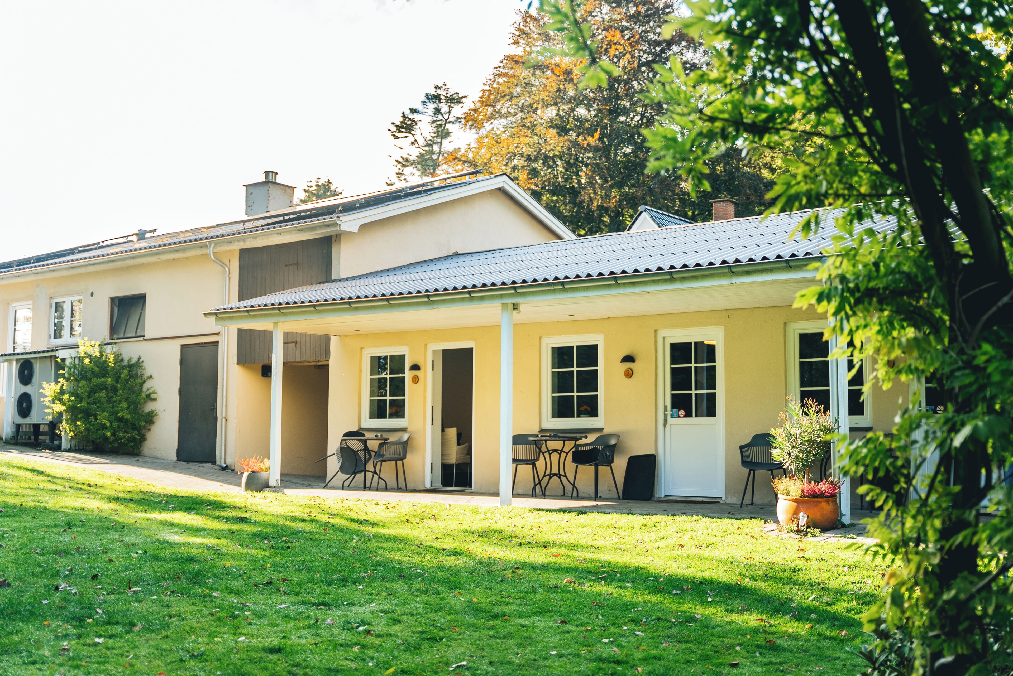 A two-story house with a covered porch, a lawn, and a garden.