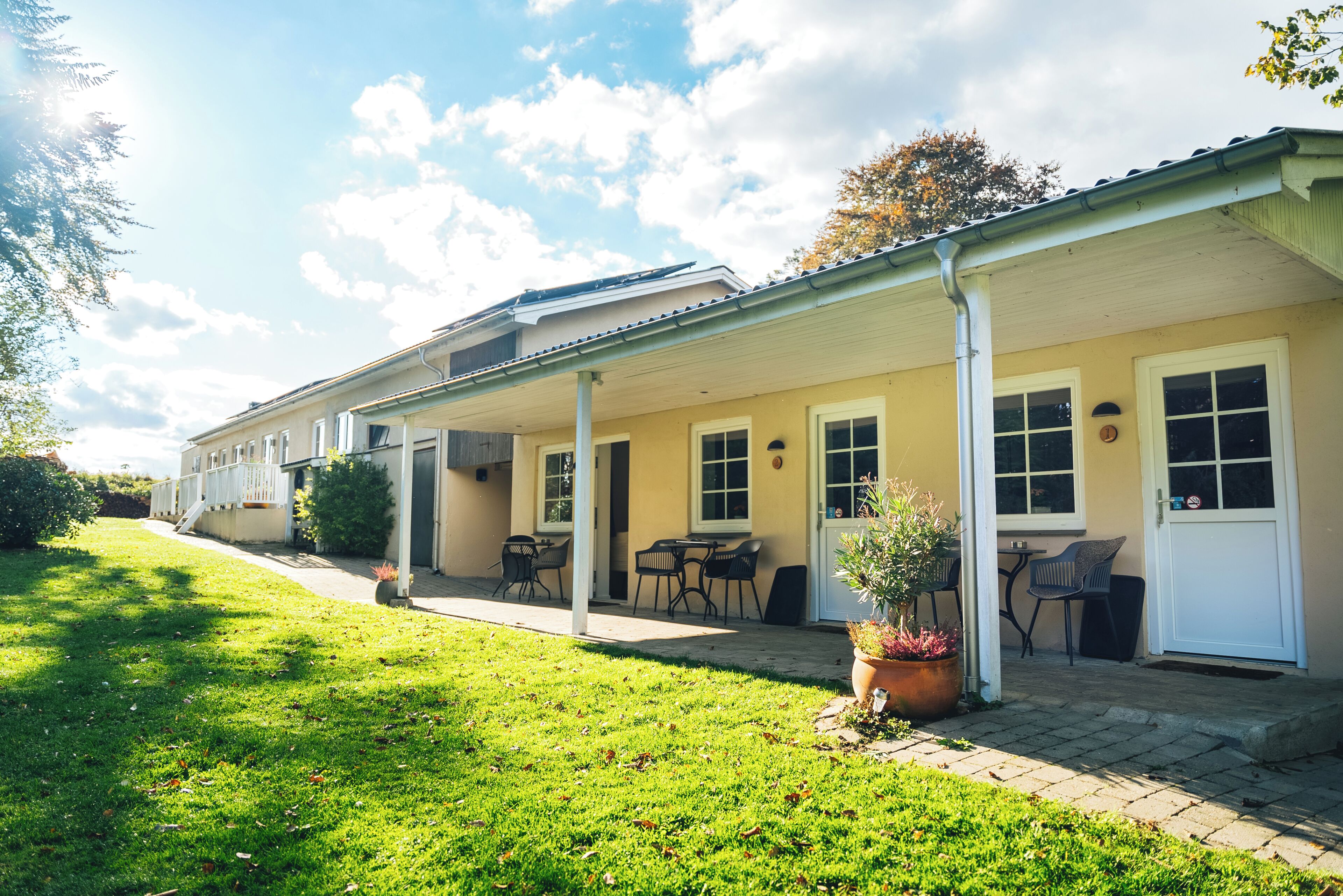 A building with a covered patio area, outdoor seating, and a well-maintained lawn.