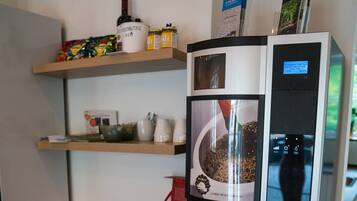 A coffee machine with a coffee pot, a milk frother, and a milk jug on a wooden table.