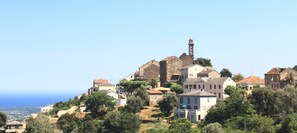 A coastal village with historic buildings, a prominent church tower, and a view of the sea. - Chambres d'hôtes Le Clos des Oliviers (Sorbo-Ocagnano)