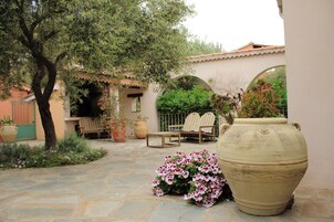 Un patio con una maceta grande, un árbol y una zona de estar con sillas.