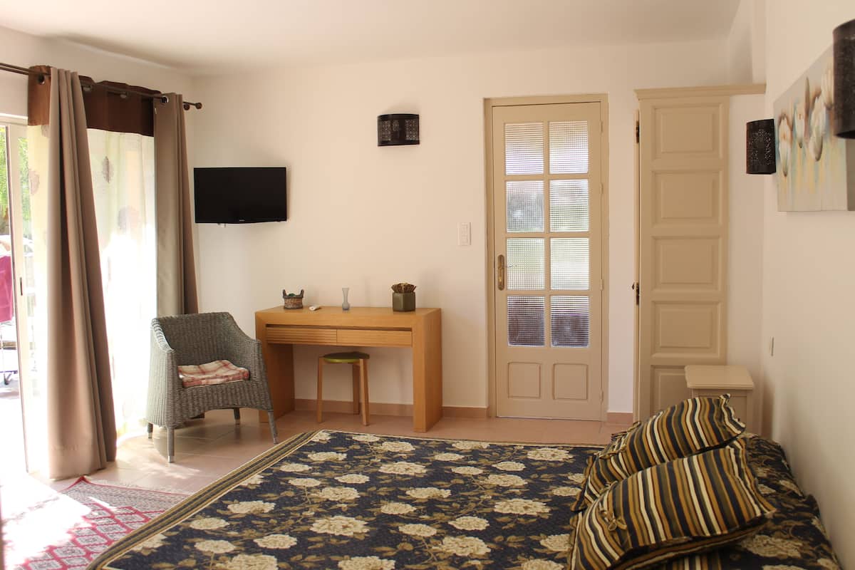 Ein Zimmer mit einem Bett, einem Schreibtisch, einem Stuhl, einem Fernseher und einer Tür.