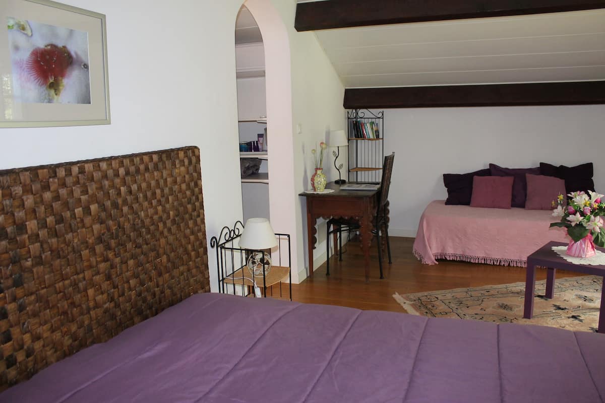 Ein Schlafzimmer mit Bett, Schreibtisch und Stuhl. Außerdem gibt es ein Bücherregal und ein Fenster.