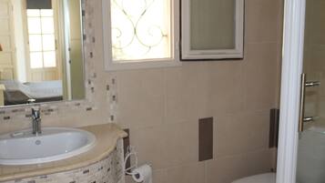 Un baño con lavamanos, inodoro y espejo.