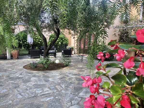 A courtyard with stone flooring, outdoor furniture, and potted plants.