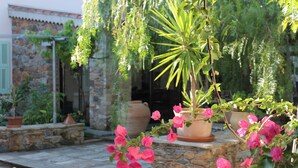 A stone building with a stone staircase, potted plants, and pink flowers. - Chambres d'hôtes Le Clos des Oliviers (Sorbo-Ocagnano)