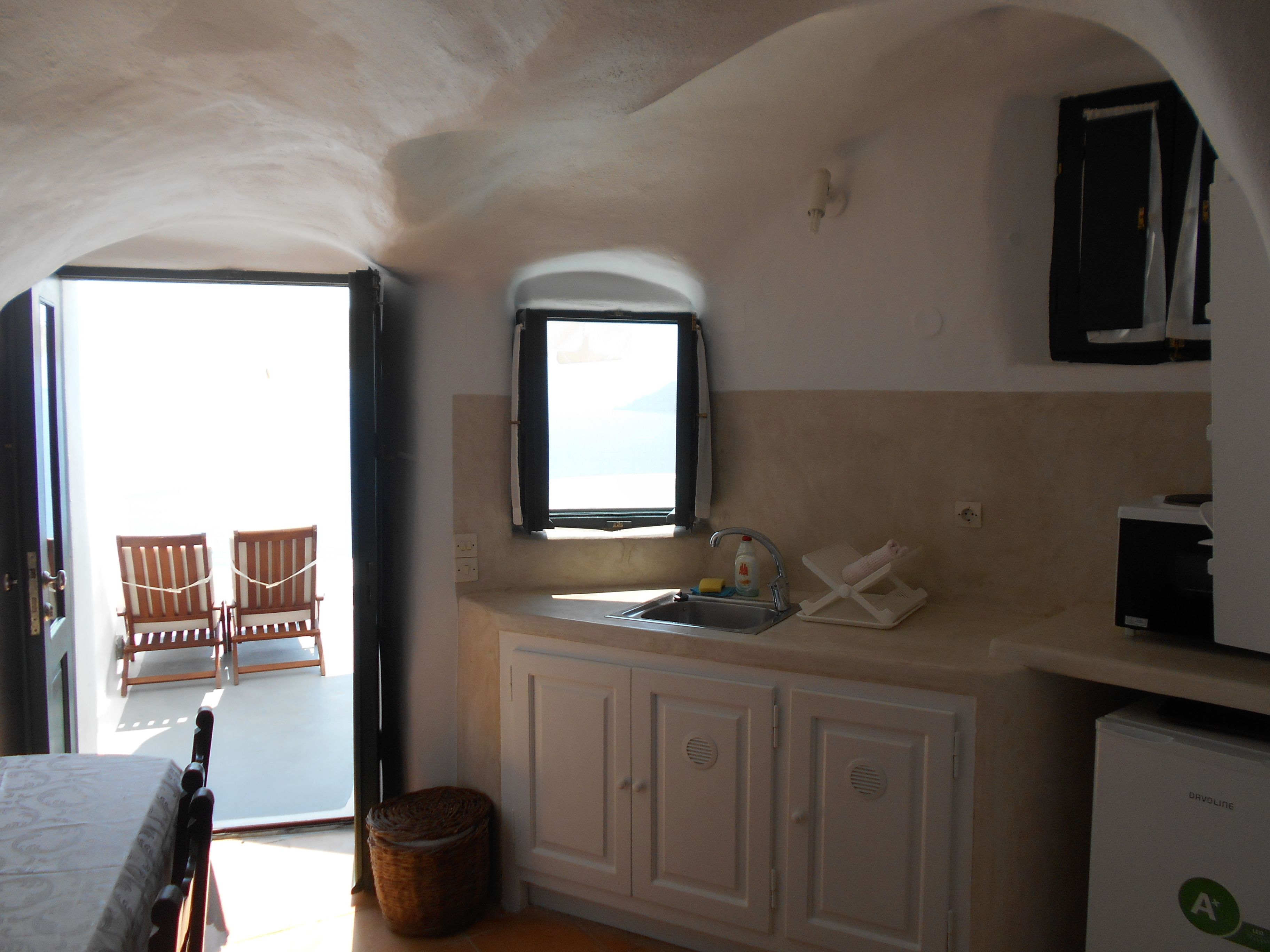 Una cocina compacta con ventana, un lavamanos y un refrigerador pequeño.