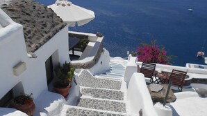 A white building with stone steps leading down to a beach. - Rimida Villas - Adults Only (Santorini)